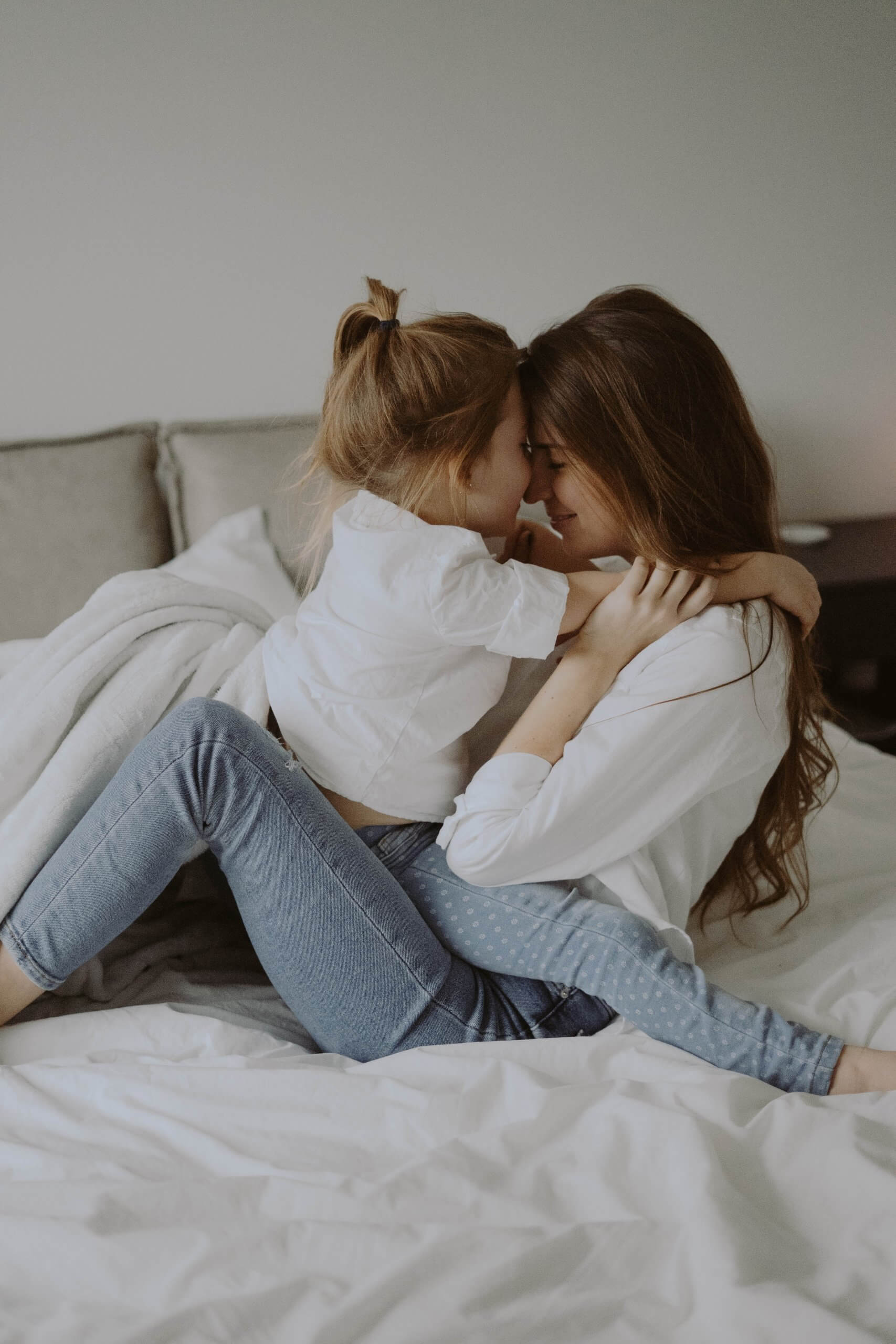 mãe e filha abraçadas na cama