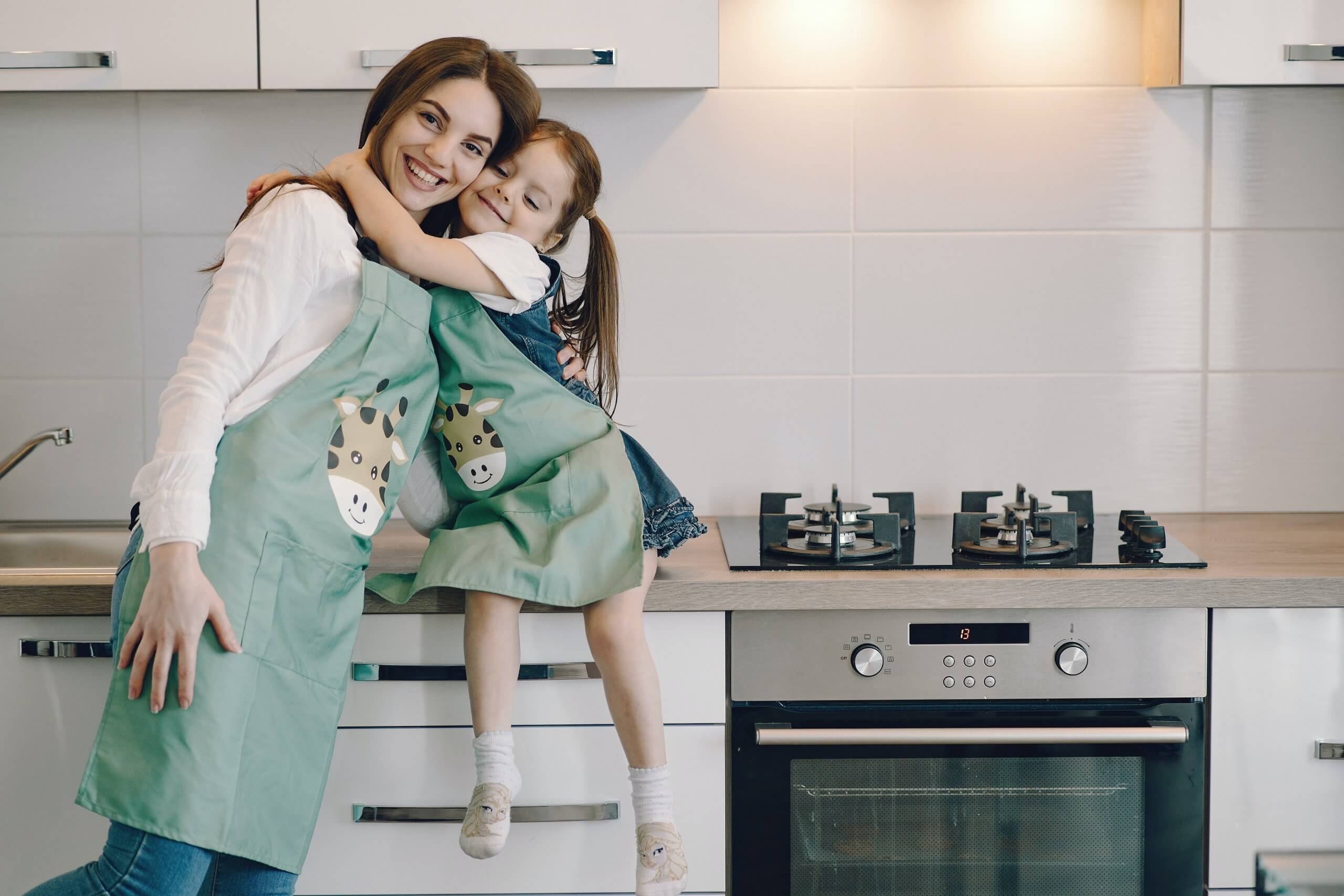 mãe e filha abraçadas na cozinha com aventais