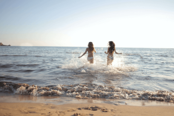 duas mulheres a correr para o mar