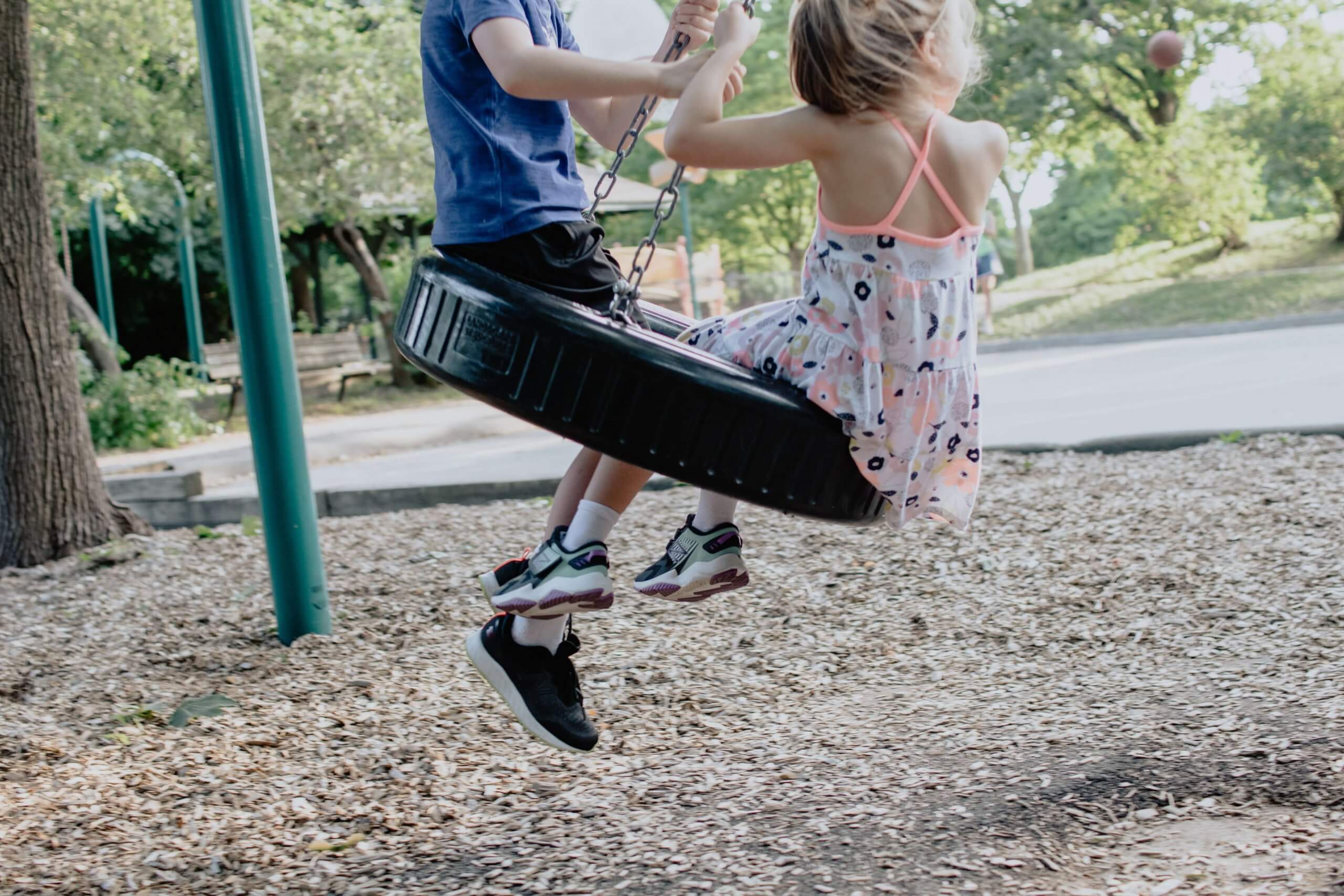 um menino e uma menina a andar num baloiço feito com um pneu