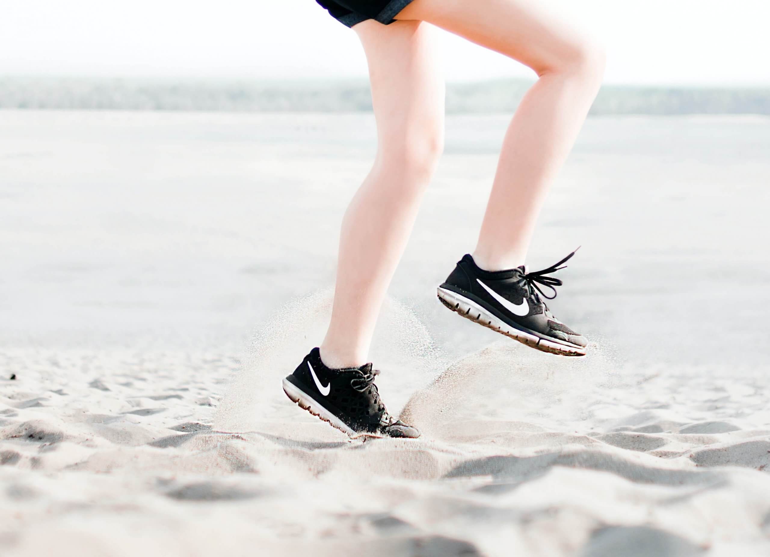 detalhe de pernas de pessoa a correr na areia